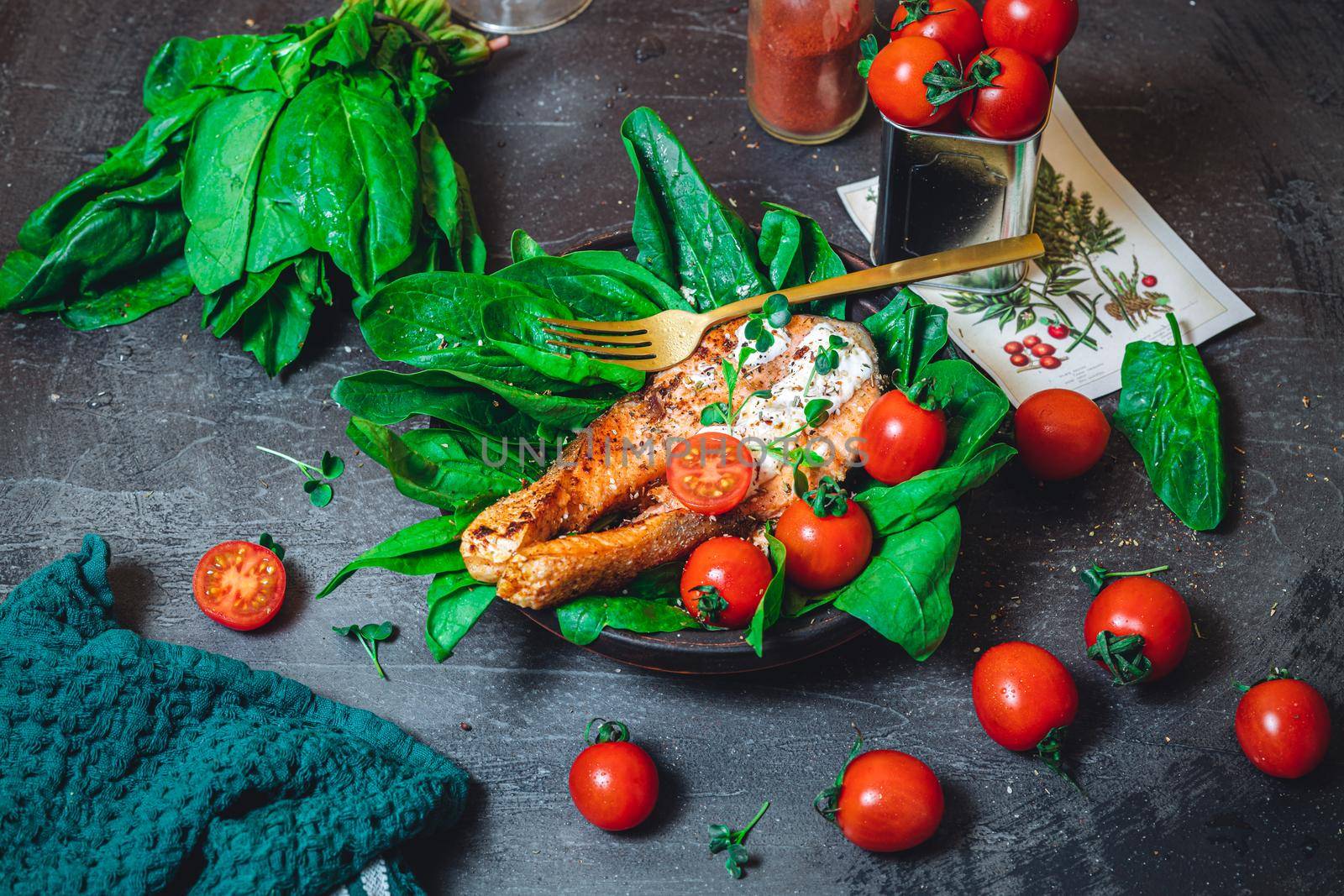 A plate with fresh green raw spinach and fried wild salmon, tomatoes and cream cheese sauce High quality photo