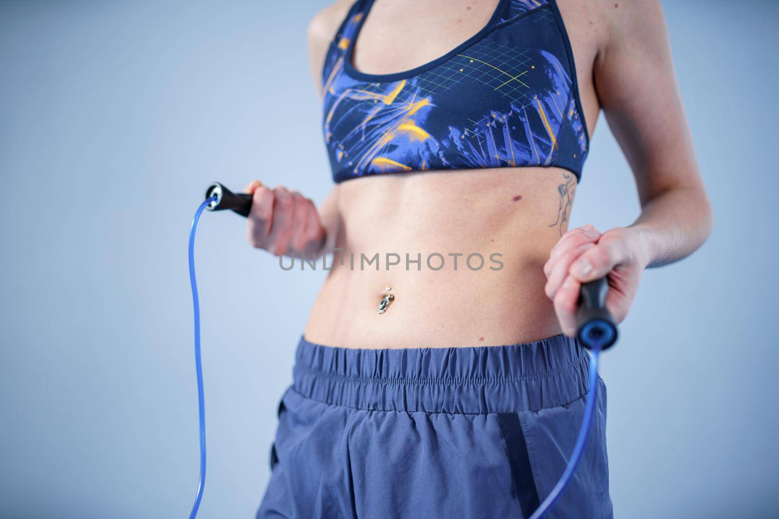 Smiling sportswoman posing with a skipping rope. Female with muscular body posing with jump rope. Fitness model. Body positivity, sport, fitness concept. Healthy lifestyle. Fit woman with jump rope by Tomashevska