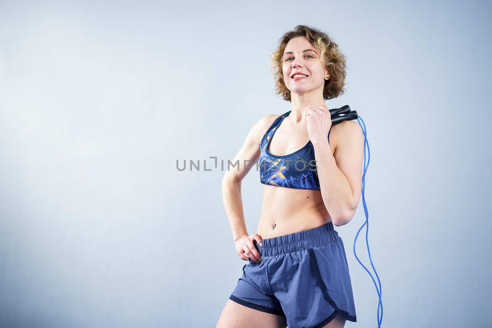 Smiling sportswoman posing with a skipping rope. Female with muscular body posing with jump rope. Fitness model. Body positivity, sport, fitness concept. Healthy lifestyle. Fit woman with jump rope.