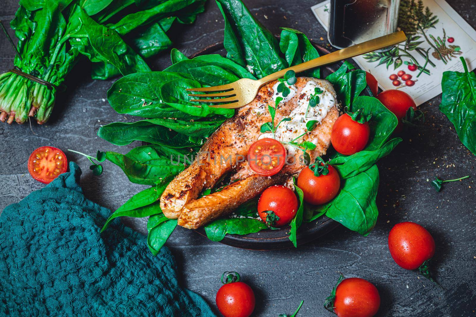 A plate with fresh green raw spinach and fried wild salmon, tomatoes and cream cheese sauce High quality photo