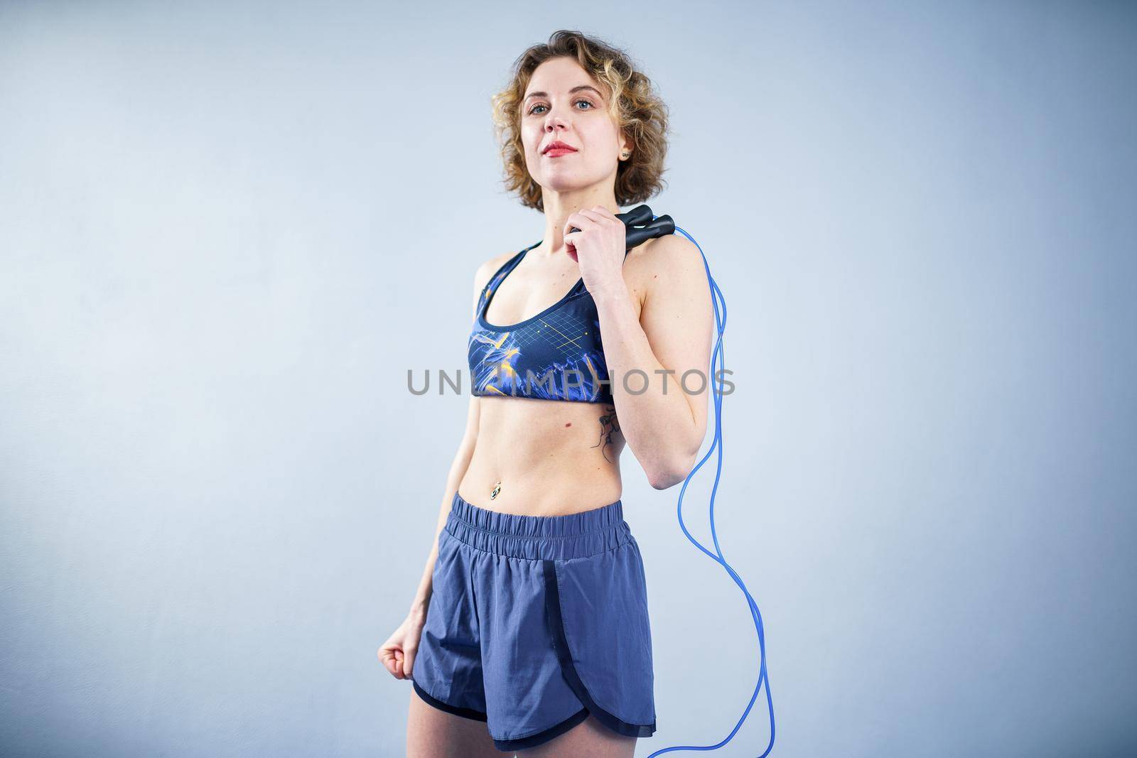 Fit woman with jump rope posing in the gym. Sport exercises healthy lifestyle concept. Sporty happy woman with skipping rope posing to the camera. Active lifestyle concept. Healthy lifestyle.