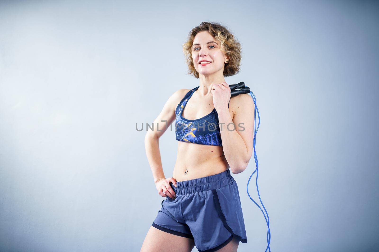 Smiling sportswoman posing with a skipping rope. Female with muscular body posing with jump rope. Fitness model. Body positivity, sport, fitness concept. Healthy lifestyle. Fit woman with jump rope.