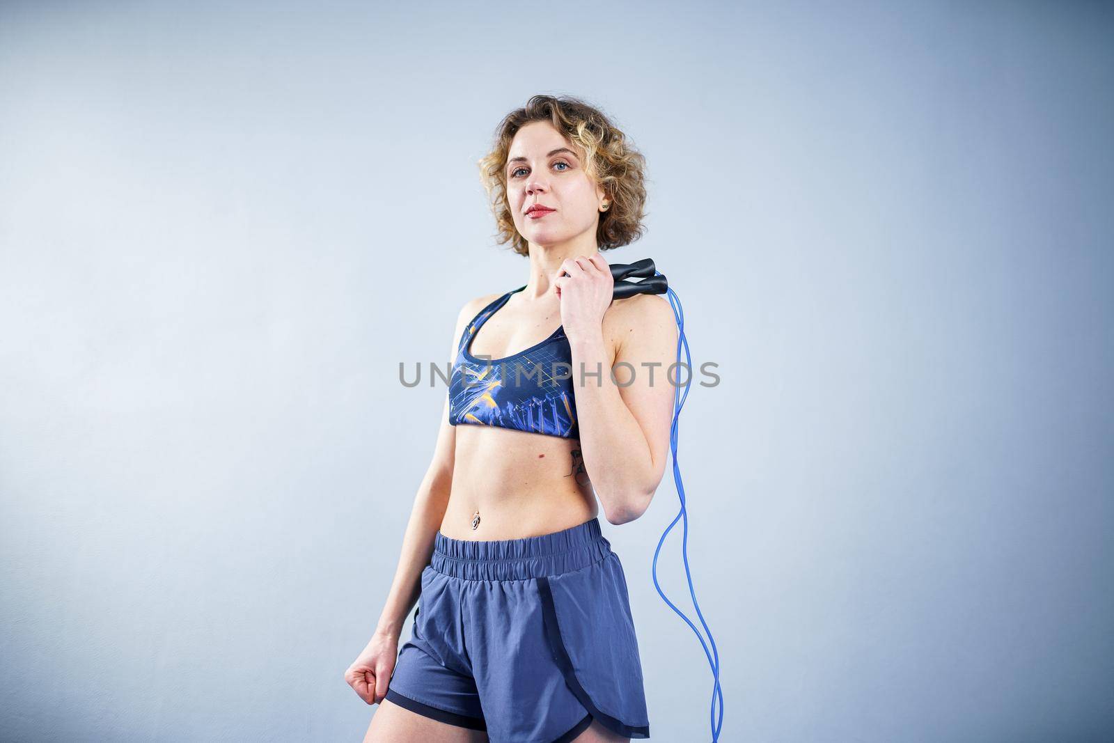 Smiling sportswoman posing with a skipping rope. Female with muscular body posing with jump rope. Fitness model. Body positivity, sport, fitness concept. Healthy lifestyle. Fit woman with jump rope by Tomashevska