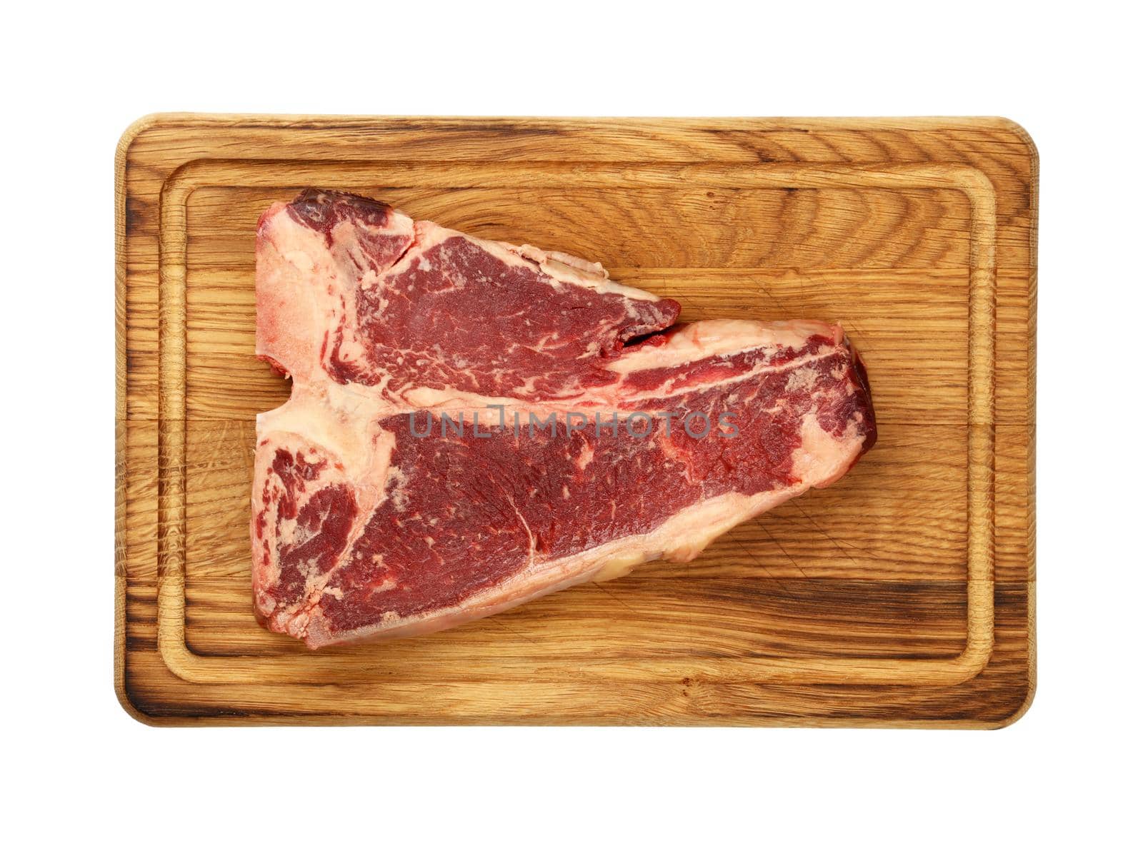 Close up one marbled raw porterhouse T-bone beef steak on wooden cutting board, isolated on white background, elevated top view, directly above
