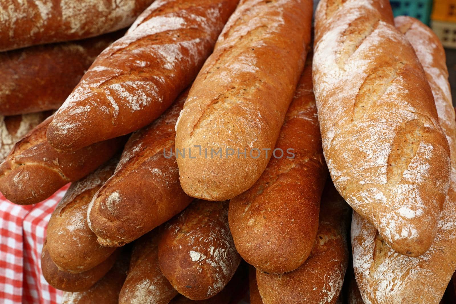 Close up several fresh French baguette bread buns on retail display of bakery store, high angle view