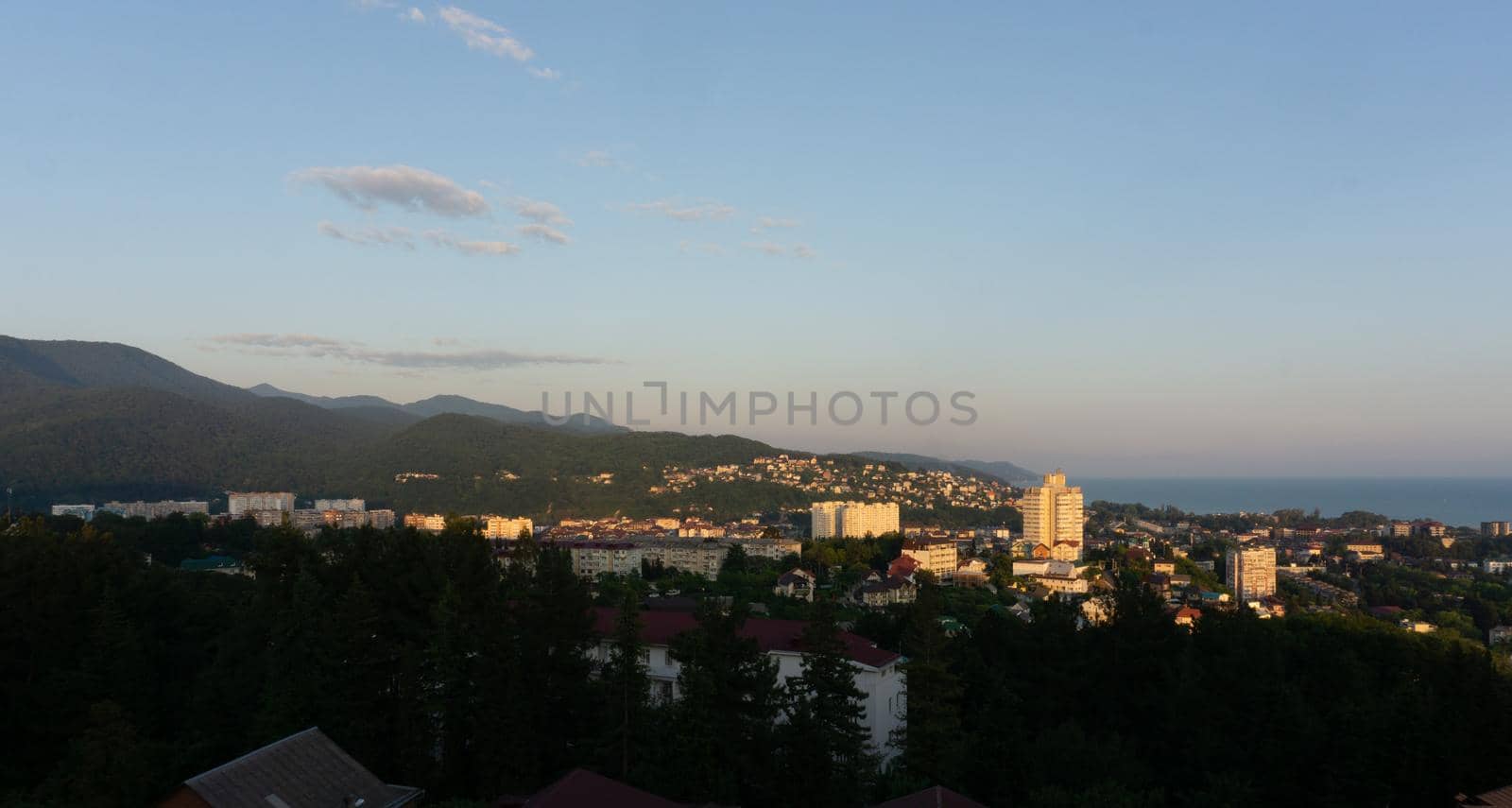 LAZAREVSKOE, SOCHI, RUSSIA - MAY, 27, 2021: Panorama of sunset in the mountains. A magical view of the sea and small town from the observation deck.