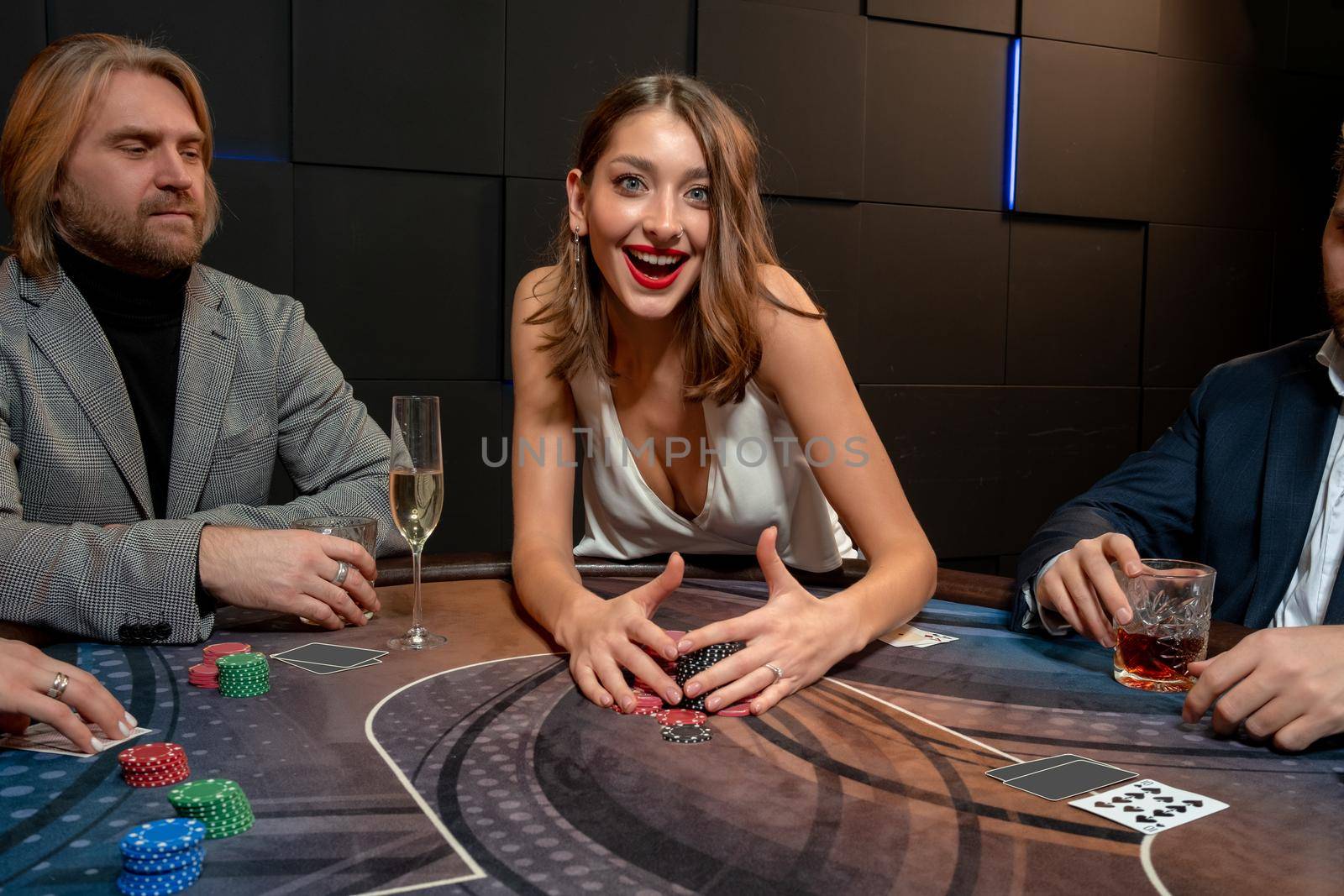 Happy excited brown-haired girl raking pile of won chips at poker table by nazarovsergey