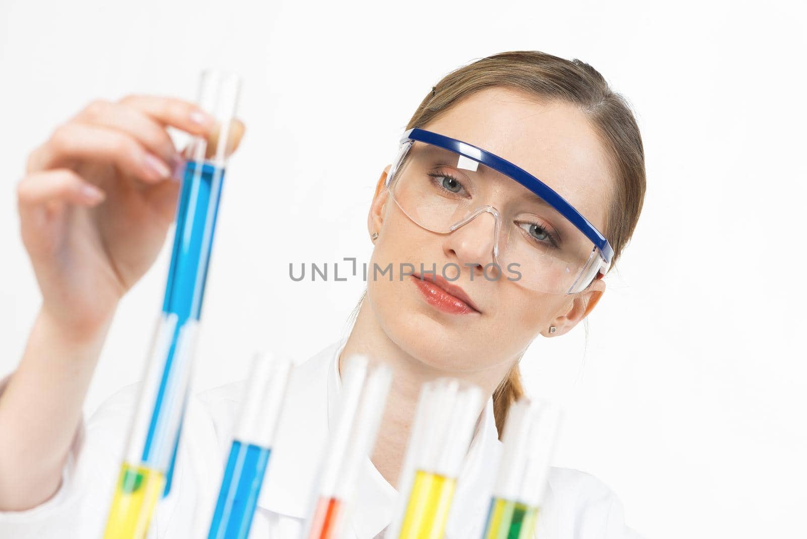 Laboratory assistant conducts experiment. Beautiful blonde woman scientist in protective goggles holding test tube with liquid. Pharmaceutical research and testing. Medical examination in clinic lab.