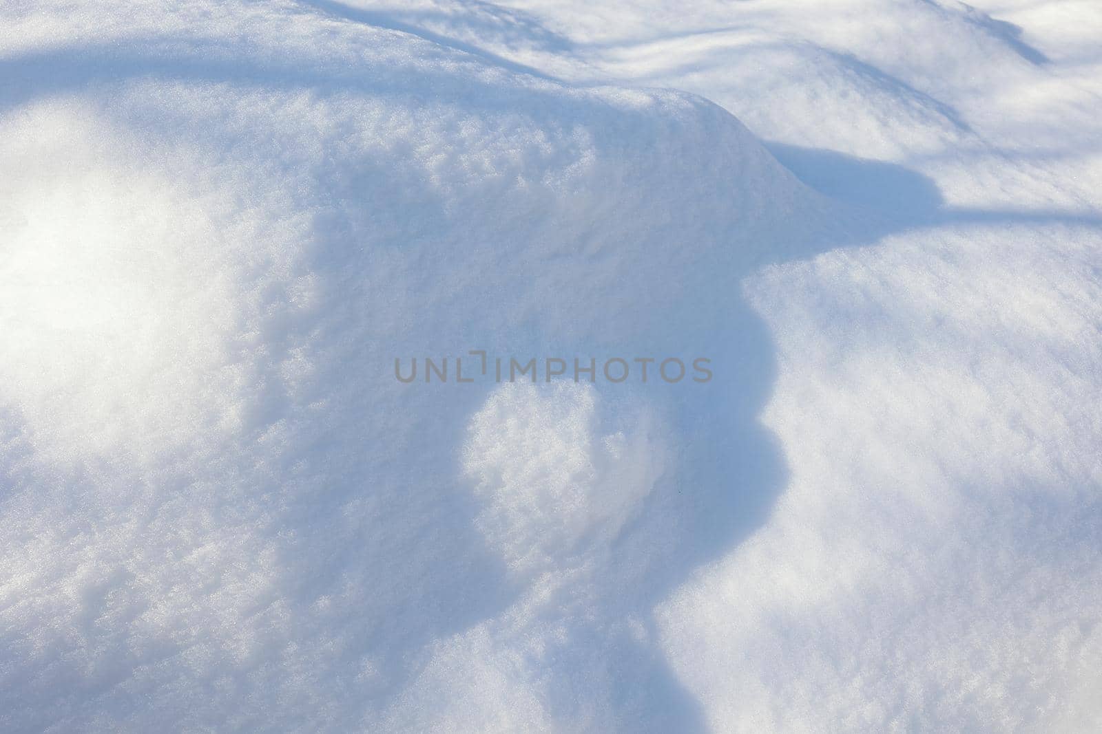 Snow texture. The wind drew patterns on the snowy surface. The wind sculpts patterns and ridges on the surface of the snow. Various shades of white on the surface of snowdrifts.