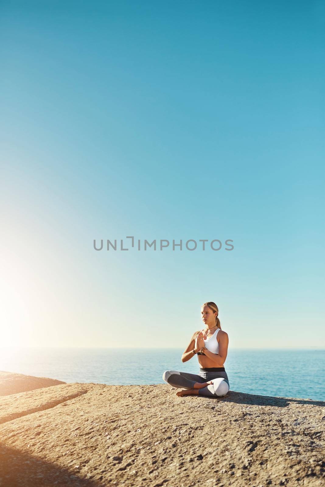 Everyone should practice yoga. Shot of a young woman doing yoga at the beach. by YuriArcurs