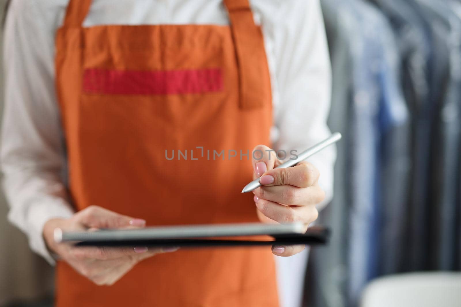 Tablet with stylus in female hands in uniform. Receiving and issuing order concept