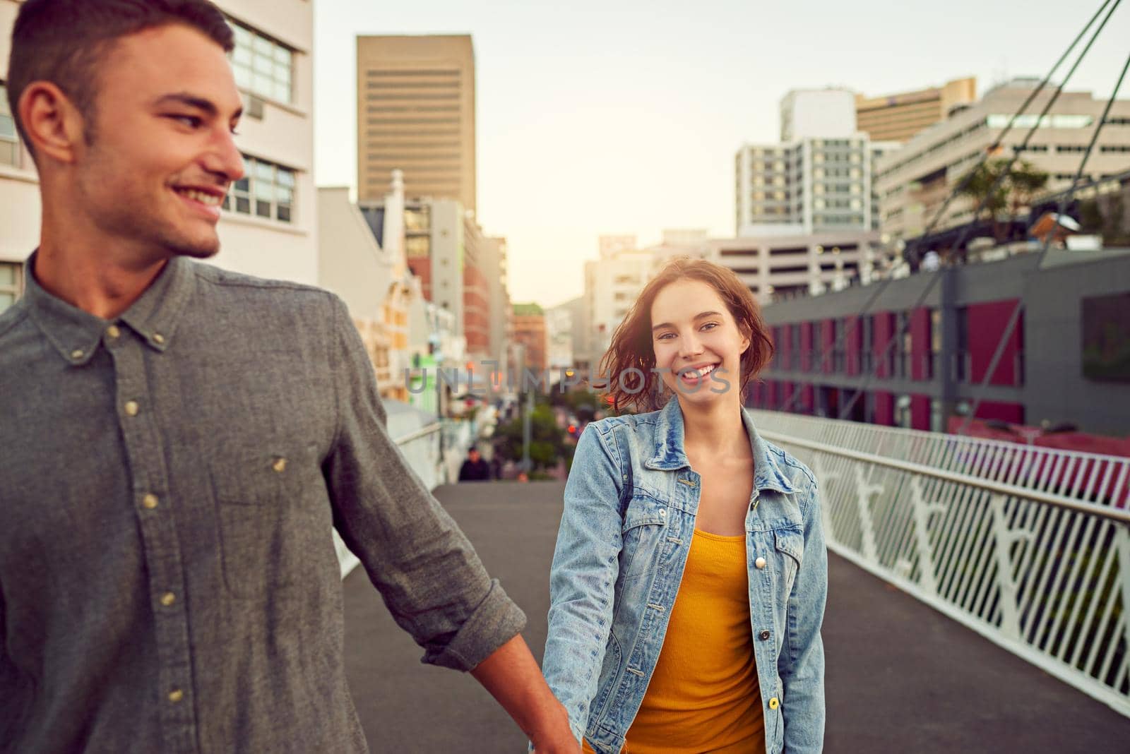 Romantic strolls in the city. Shot of a happy young couple enjoying a romantic walk together in the city. by YuriArcurs