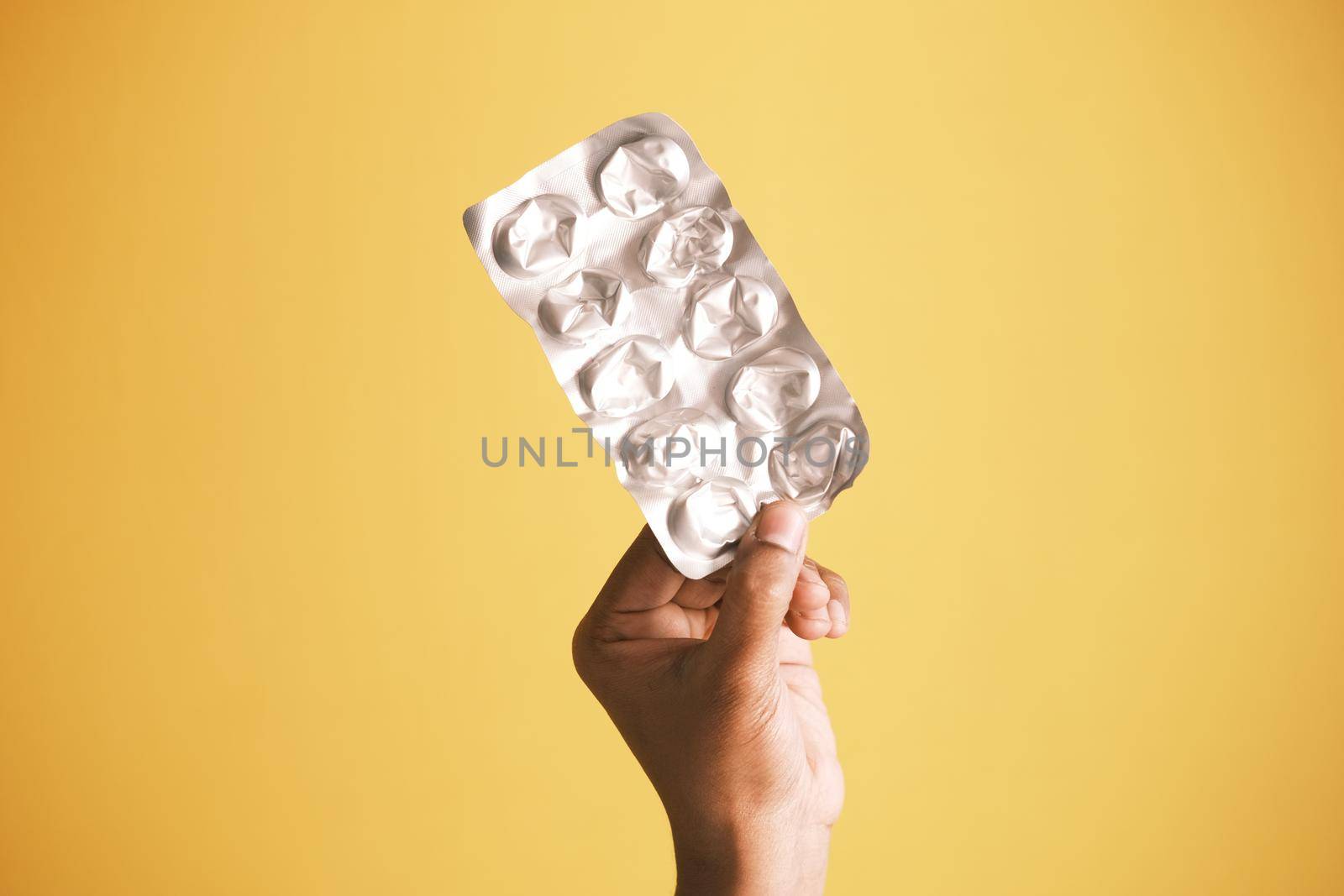 holding empty pills of blister pack against yellow background ,