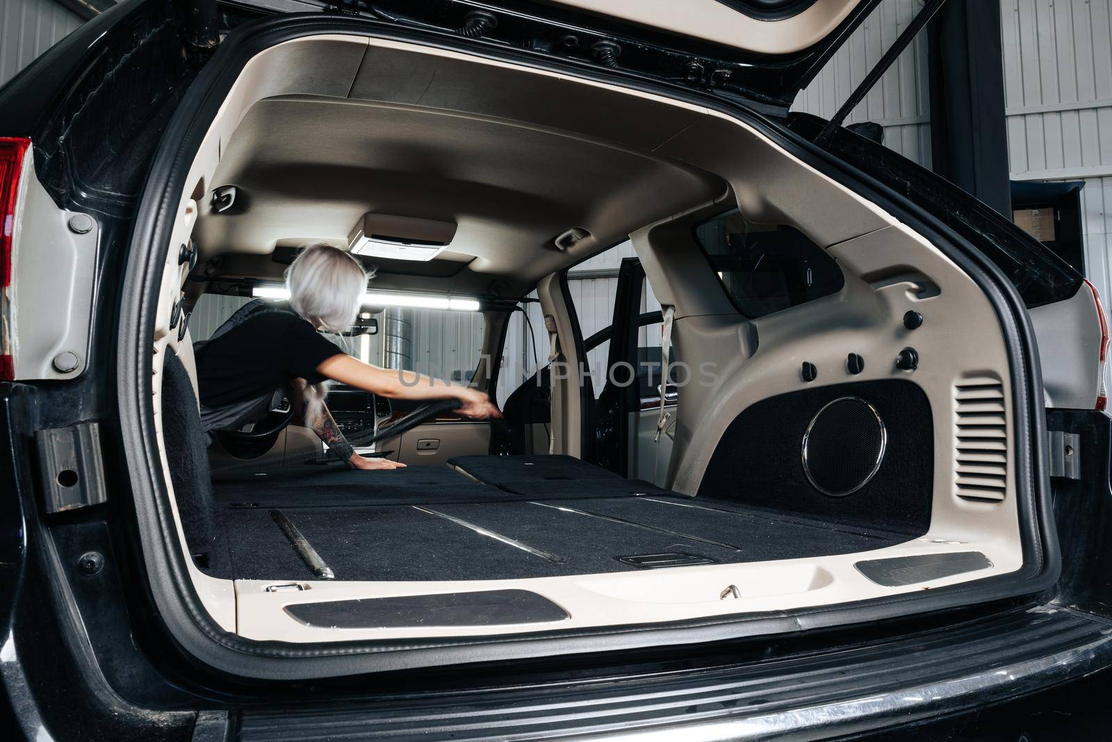 Worker woman vacuum cleaning dust interior inside car in car wash, close up