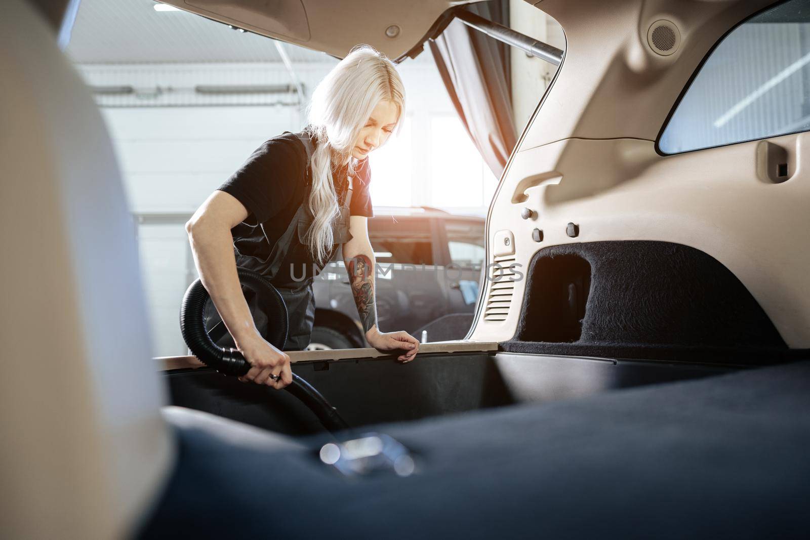 Worker woman vacuum cleaning dust interior inside car in car wash, close up