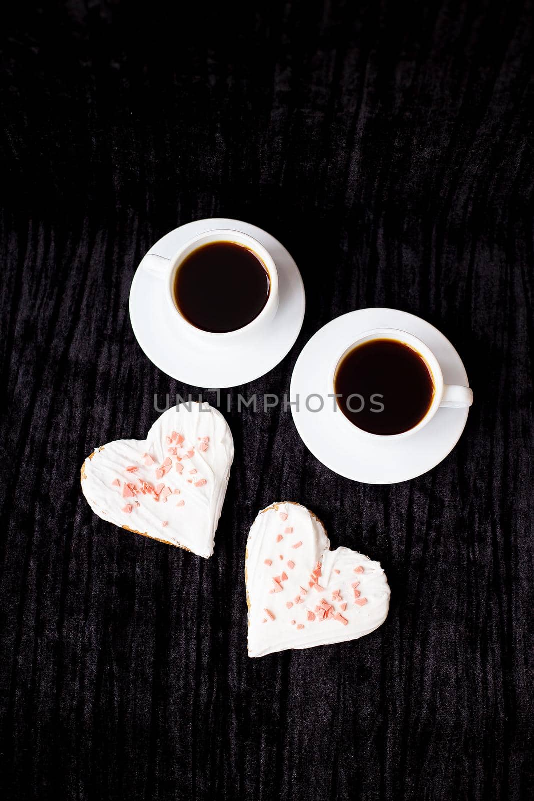 on a black background are two cups of coffee and biscuits in the form of heart by sfinks