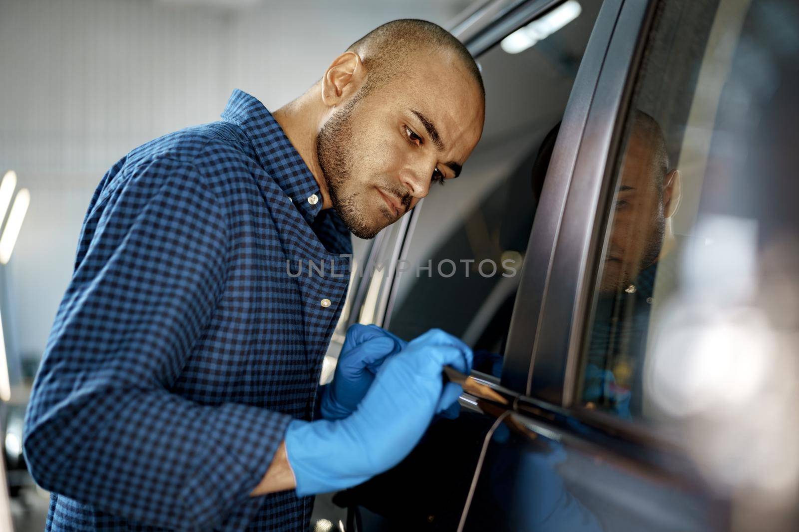 African American man car service worker applying nano coating on a car, close up
