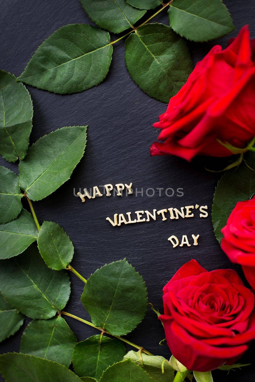 The inscription Happy Valentine on a black background with red roses