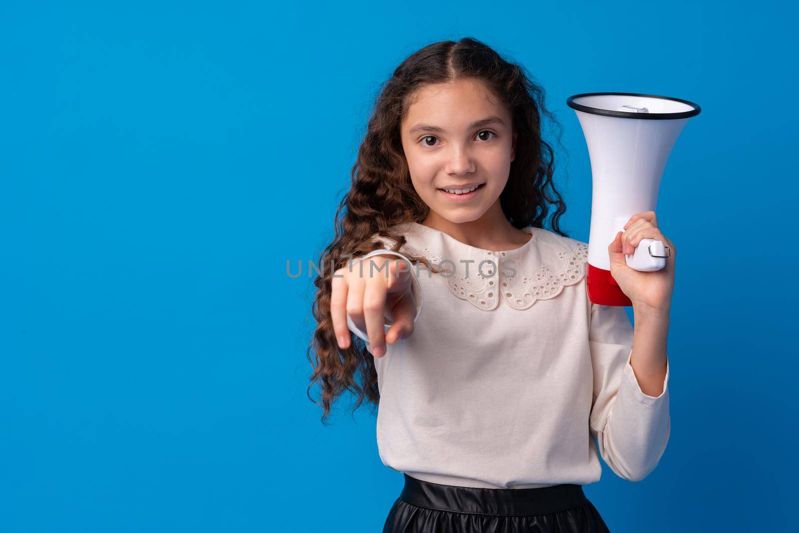 Cute schoolgirl holding megaphone against blue background, close up
