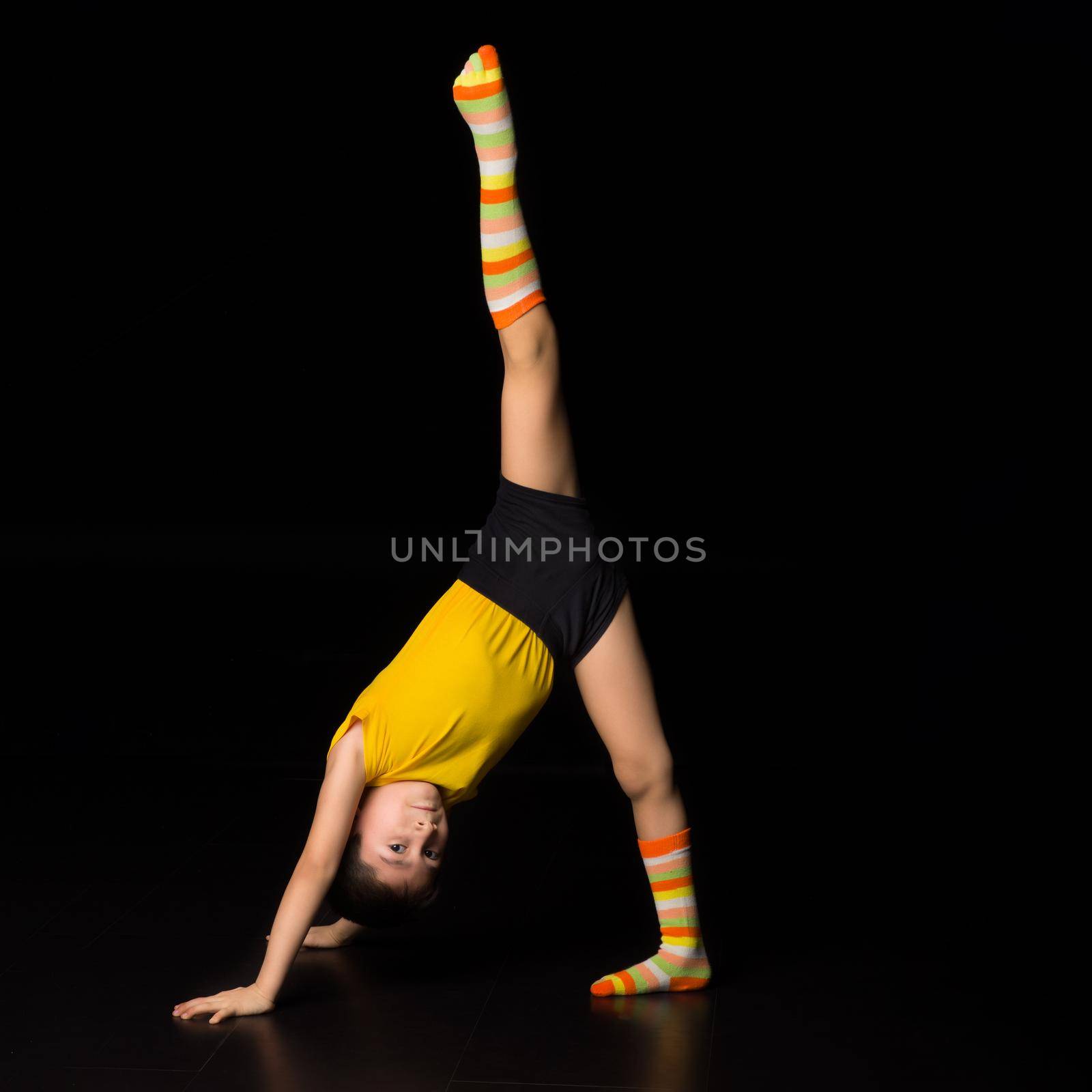 Boy gymnast doing splits leaning on his hands by kolesnikov_studio