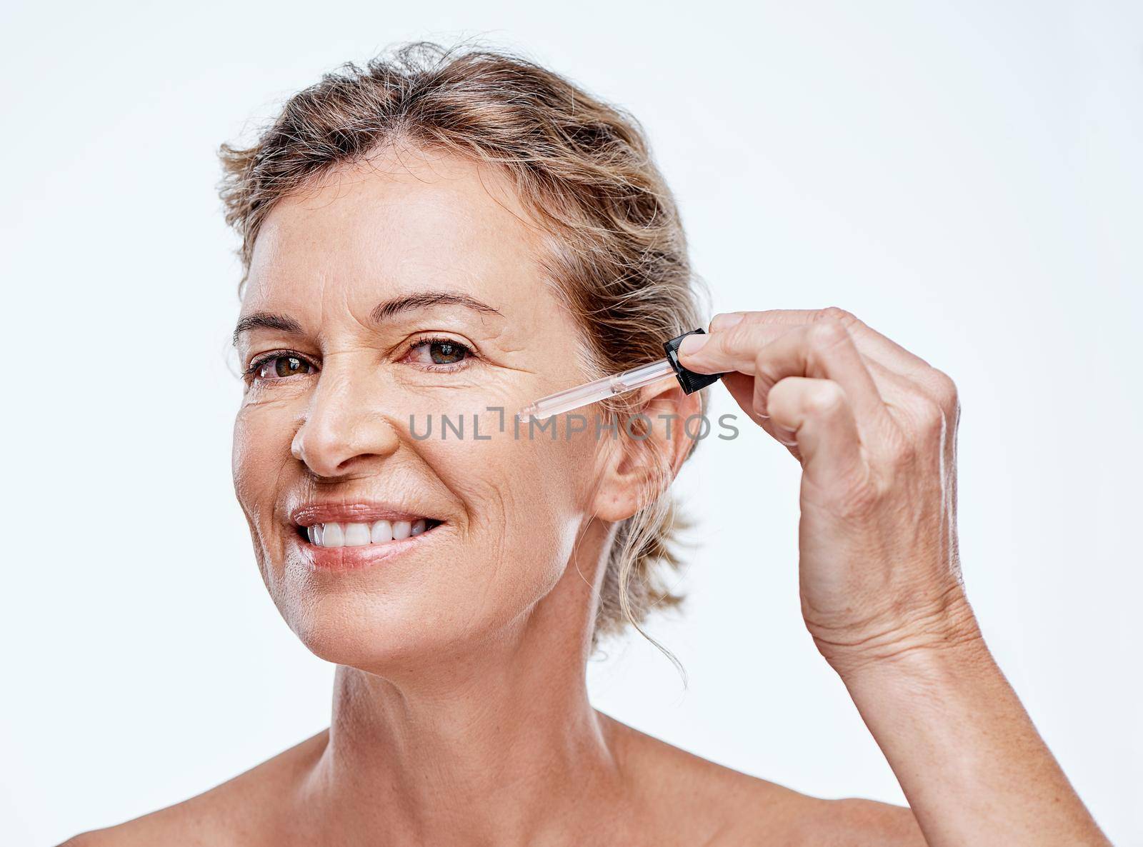 Shot of a mature woman posing with a serum dropper against her face