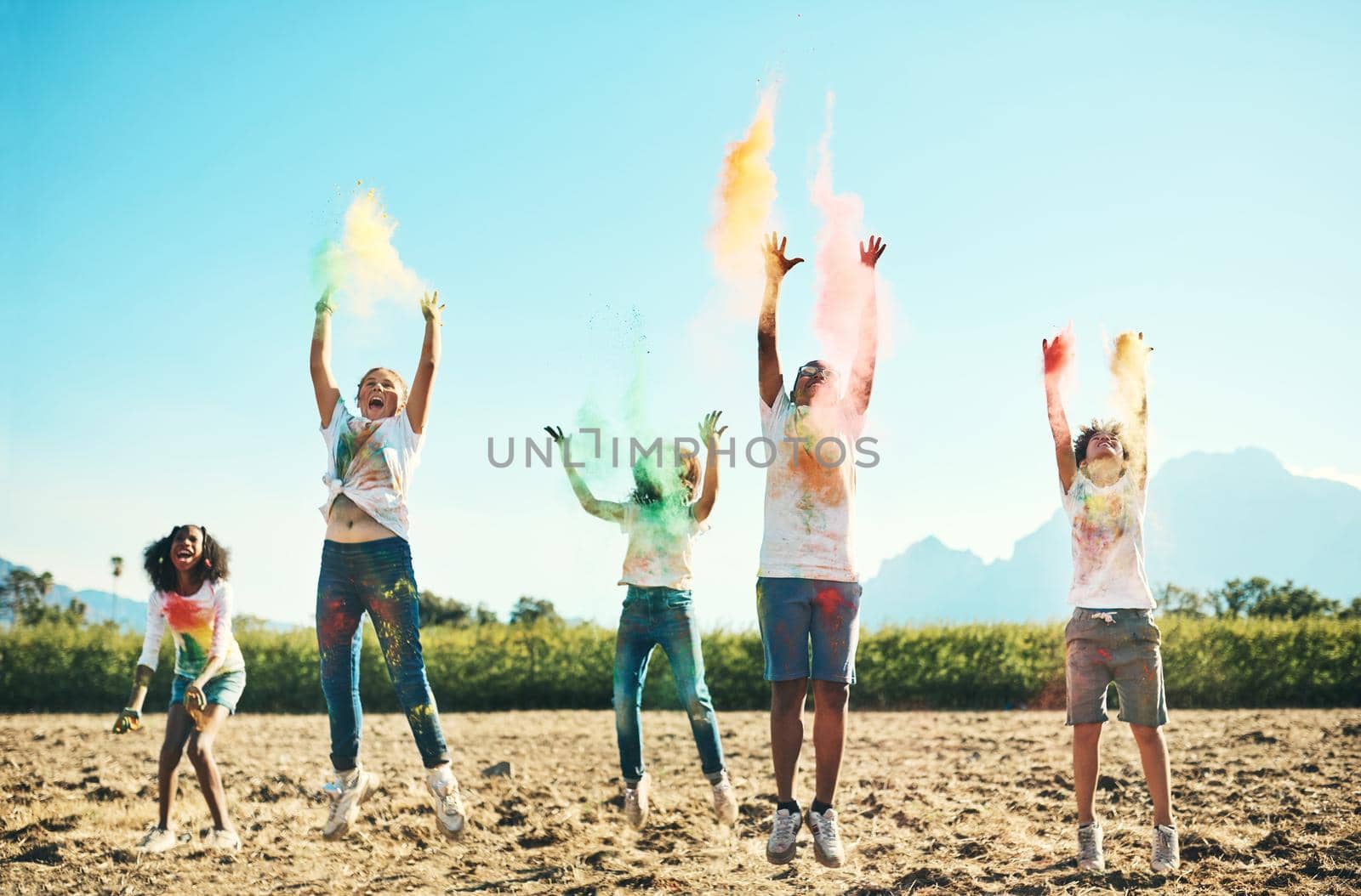 Time flies when you're having fun. Shot of a group of teenagers having fun with colourful powder at summer camp. by YuriArcurs