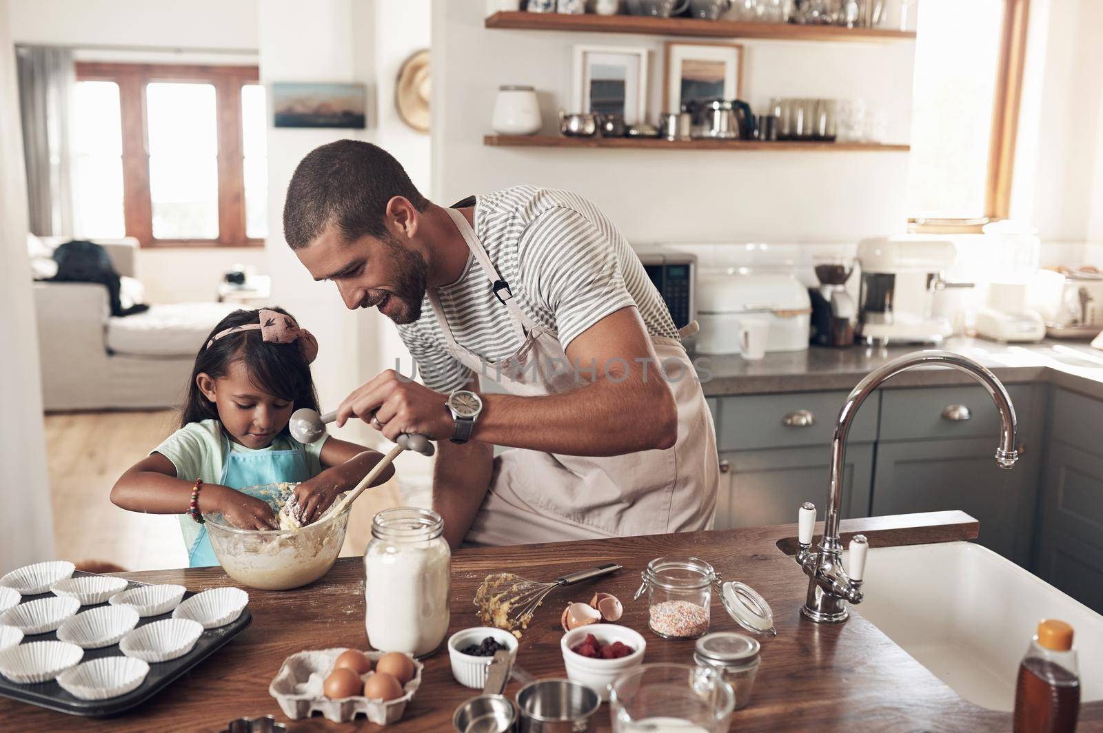 Shot of a father teaching his daughter how to bake in the kitchen at home