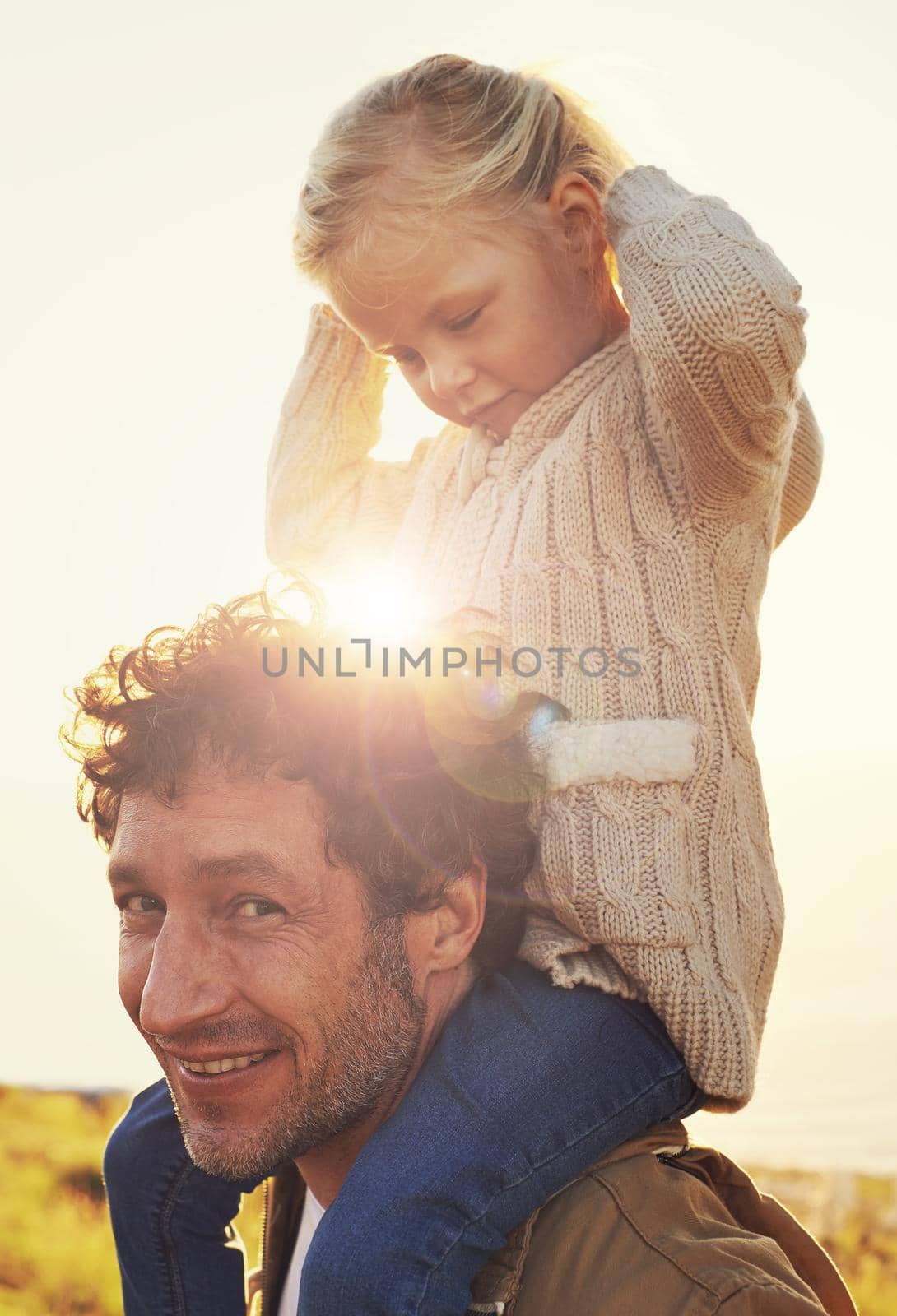They have the most fun together. Shot of a father carrying his little girl on his shoulders while walking outdoors. by YuriArcurs