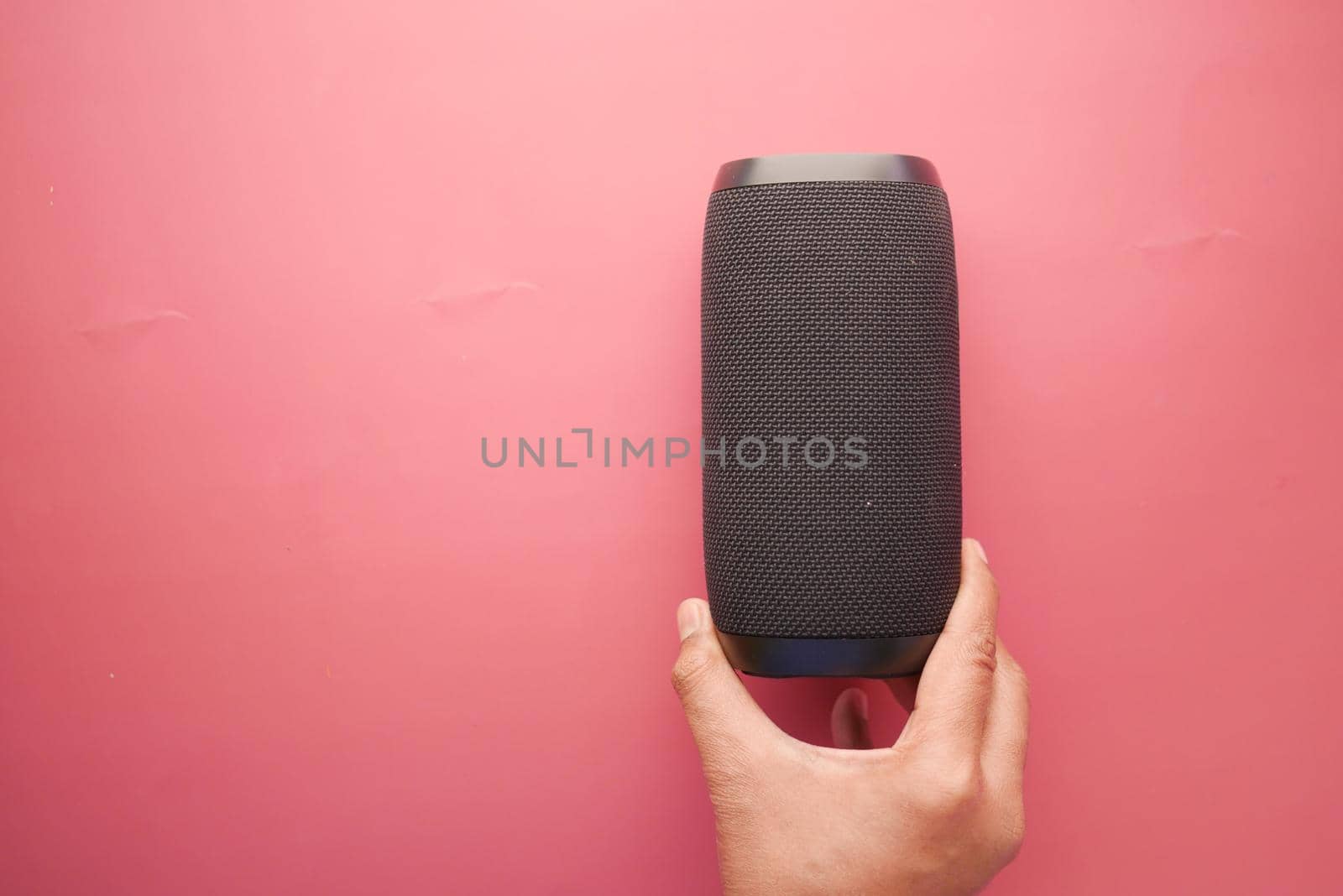 man's hand using smart speaker on red background .