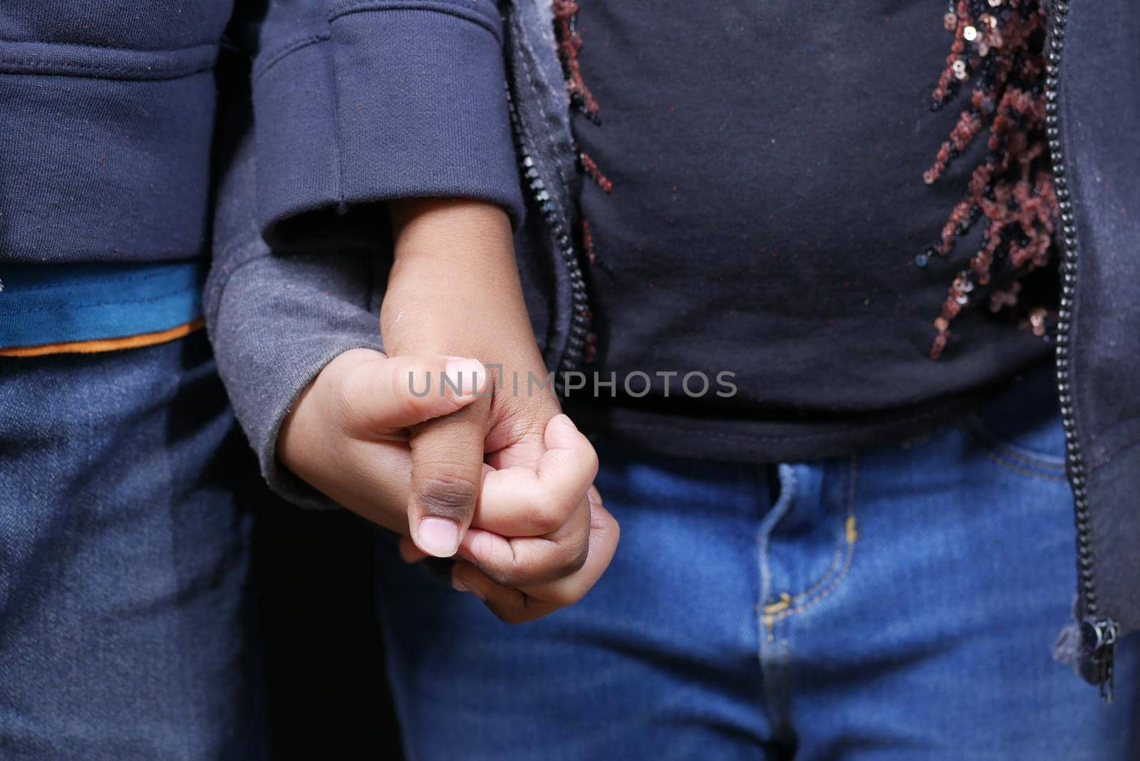 detail shot of child girl holding hand of her bother ,