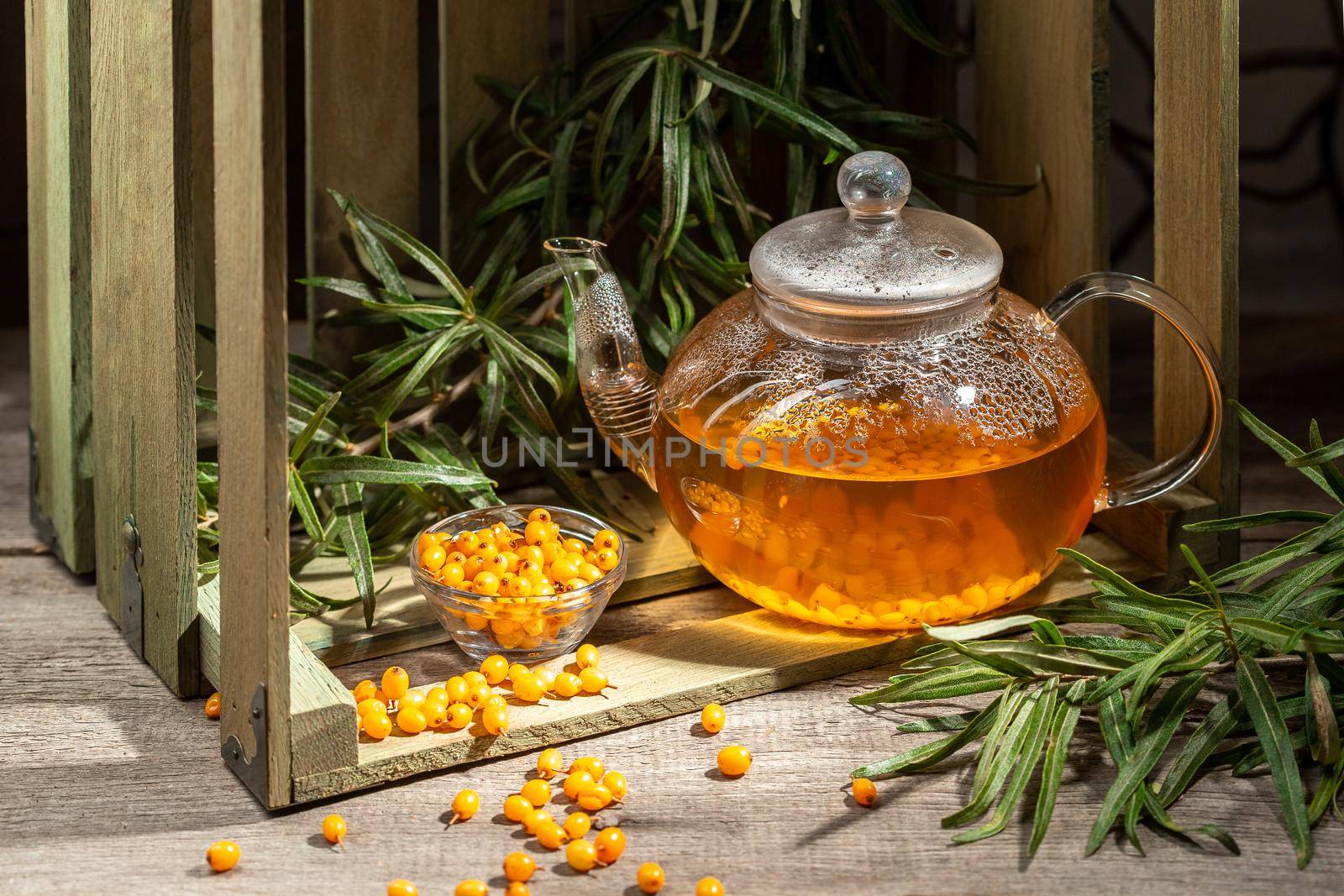 Hot winter drink made from Sea Buckthorn berries in a glass kettle on wooden table