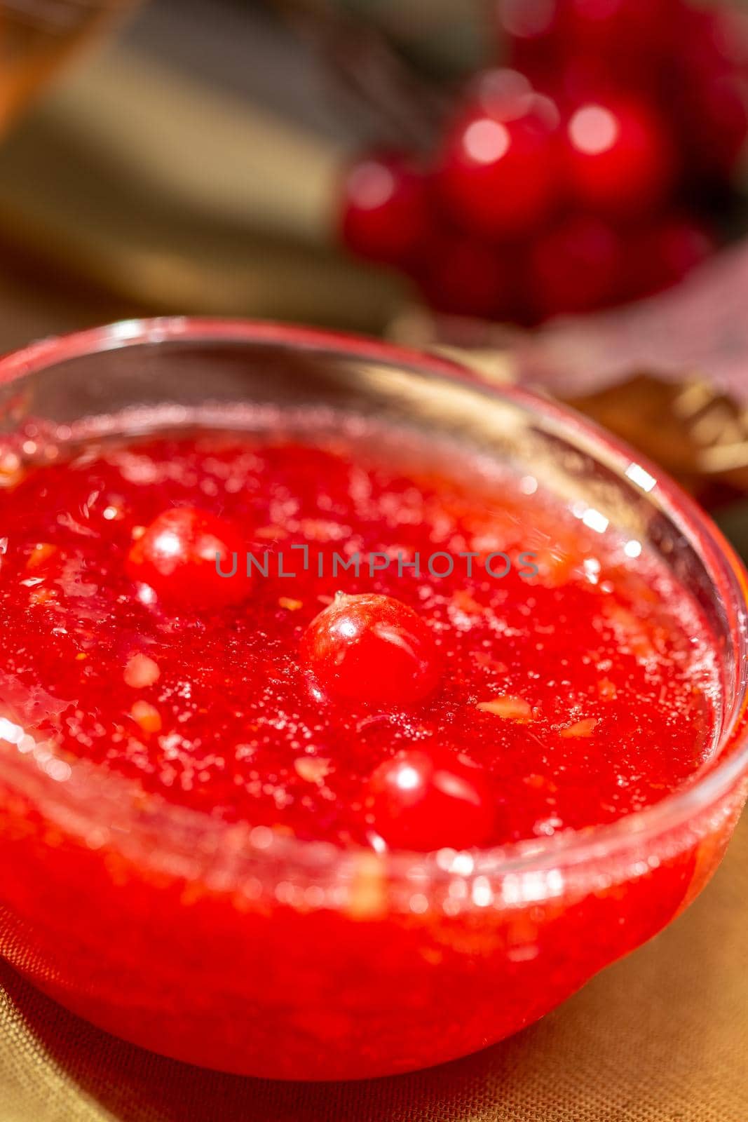 Viburnum jam in a glass bowl on the wooden table by Syvanych