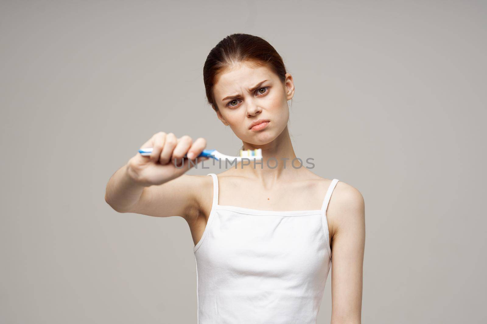 pretty woman toothpaste brushing teeth dental health light background. High quality photo