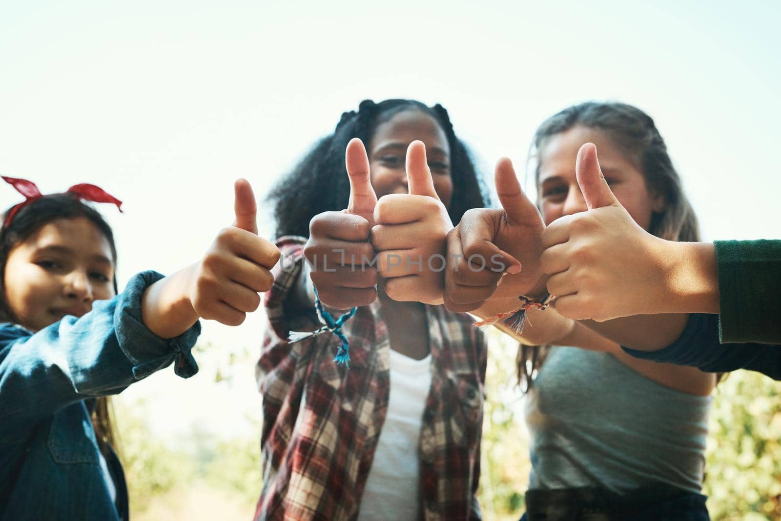 Shot of a group of teenage girls showing thumbs up at summer camp