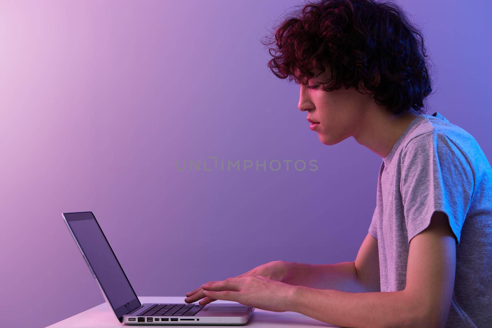 curly guy sitting at the table gaming laptop Lifestyle technology. High quality photo