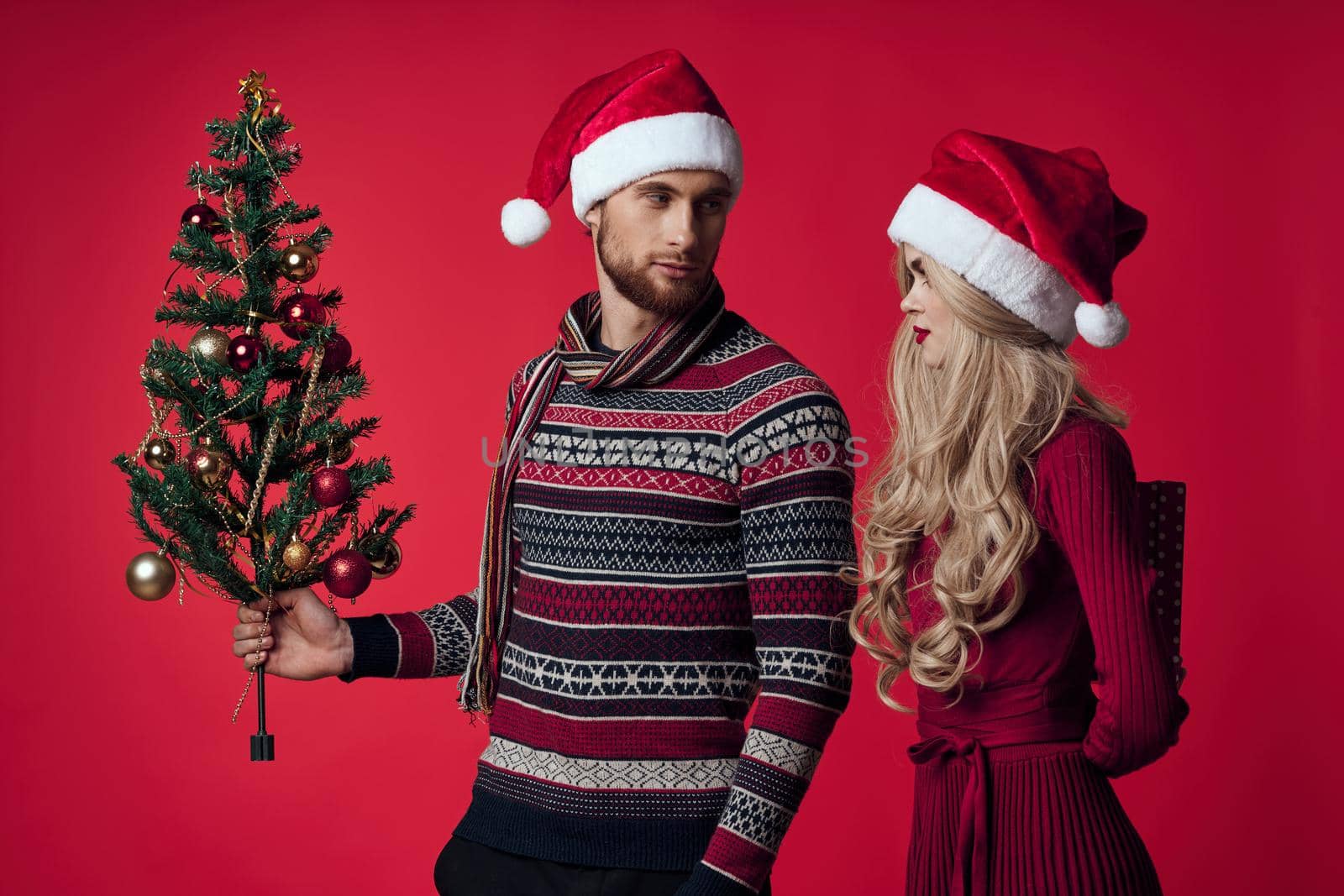 young couple christmas decorations holiday posing red background. High quality photo