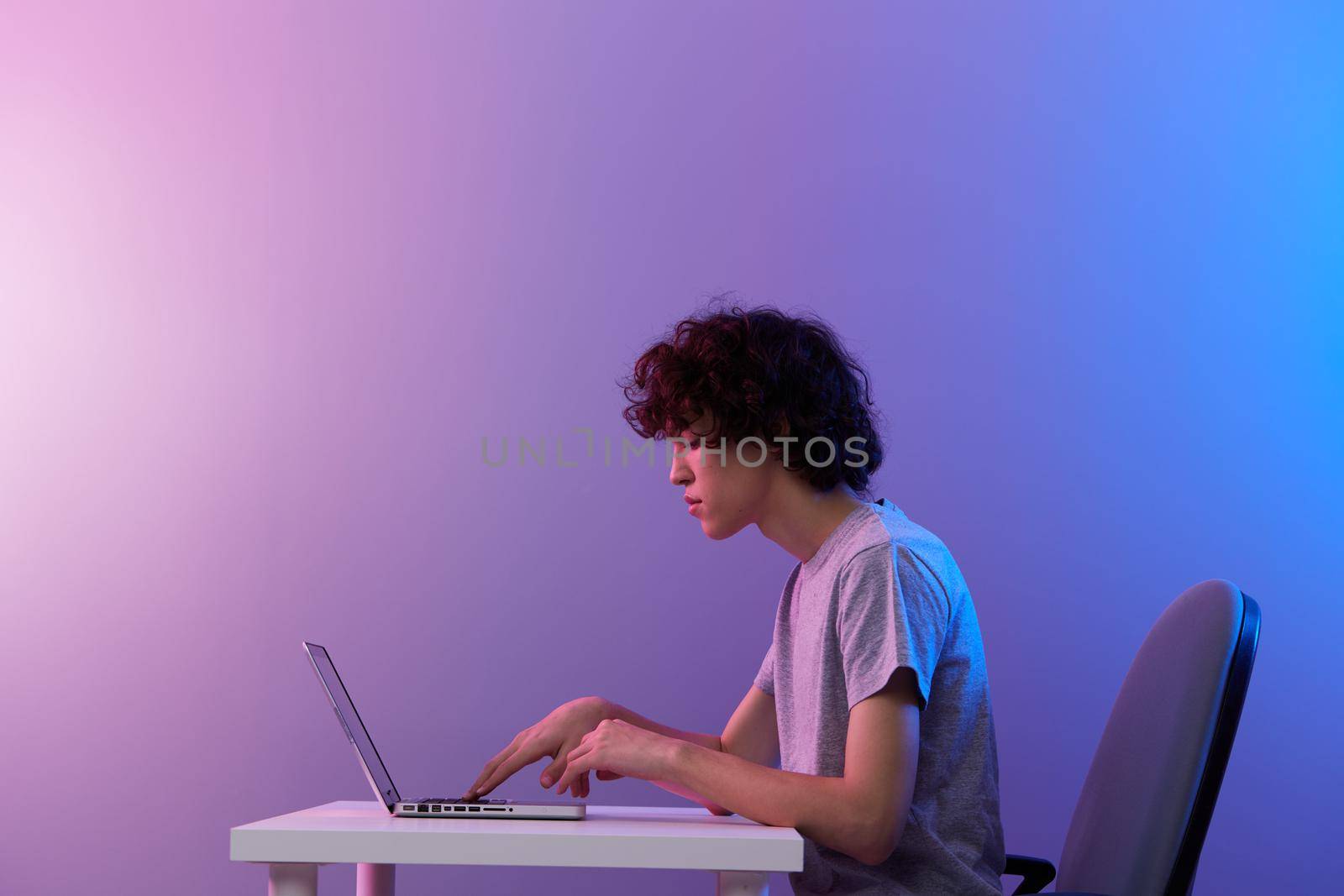 gamer cyberspace playing with in front of a laptop violet background. High quality photo