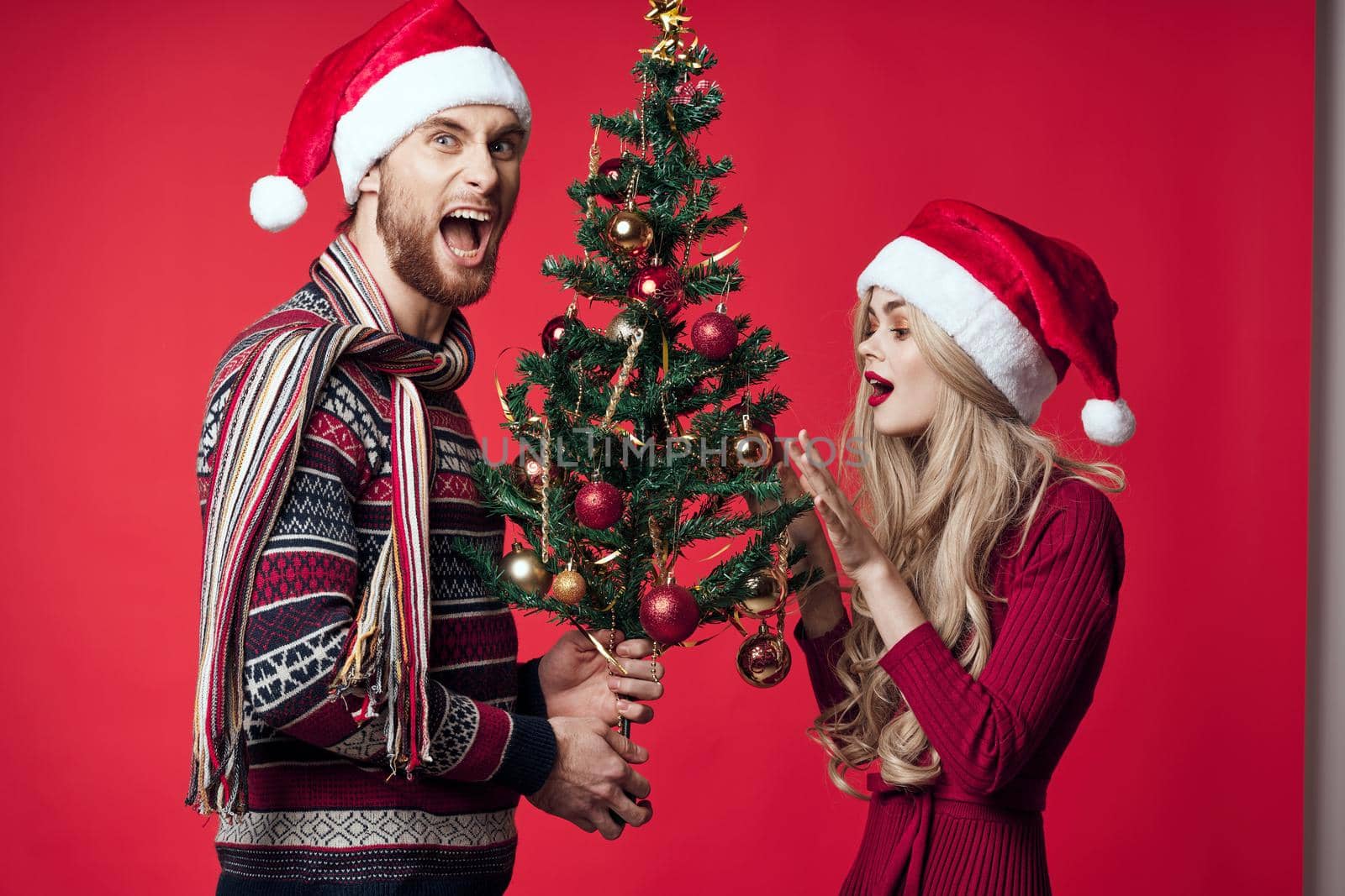 man and woman Christmas tree toys gifts holiday red background. High quality photo