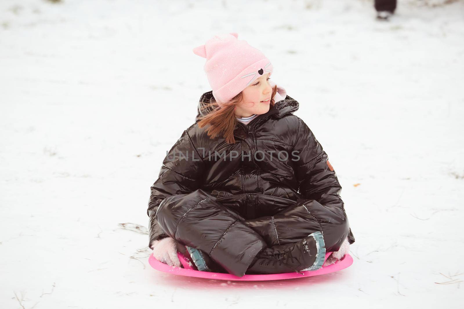 Active girl sliding down the hill. Happy child having fun outdoors in winter on sledge. Family time