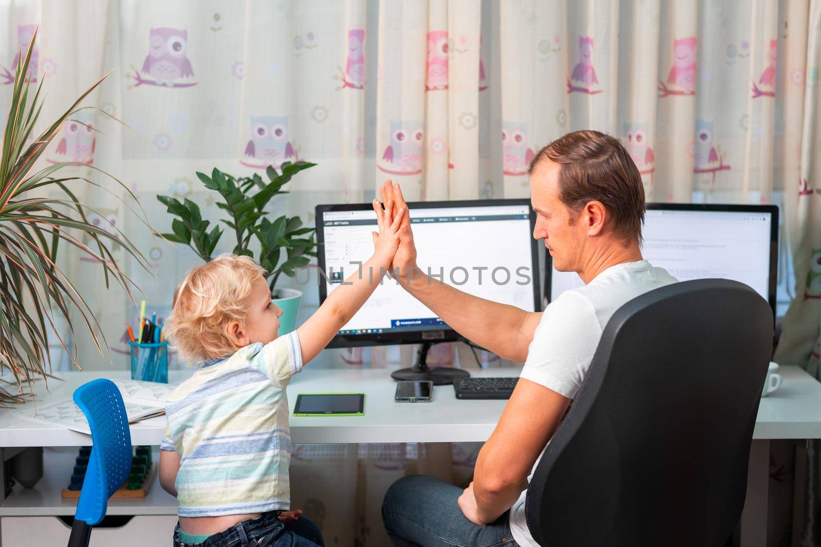 Father with kid trying to work from home during quarantine. Stay at home, work from home concept during coronavirus pandemic