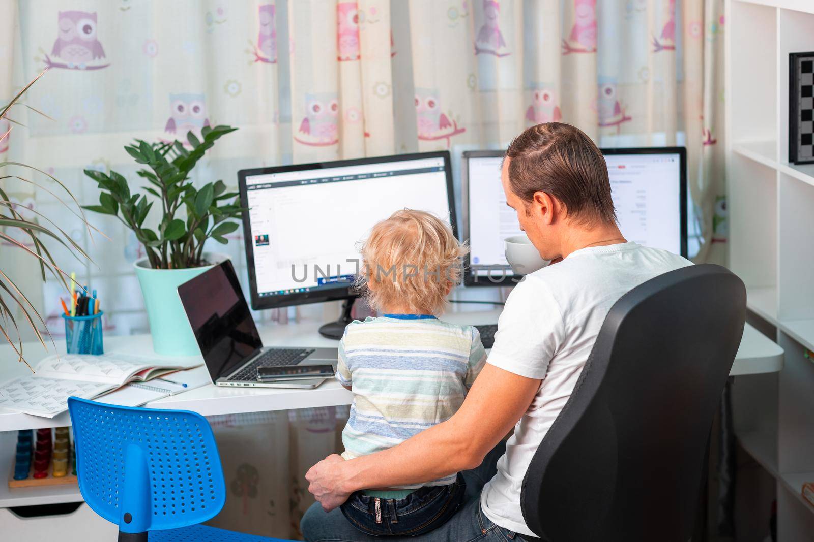 Father with kid trying to work from home during quarantine. Stay at home, work from home concept during coronavirus pandemic