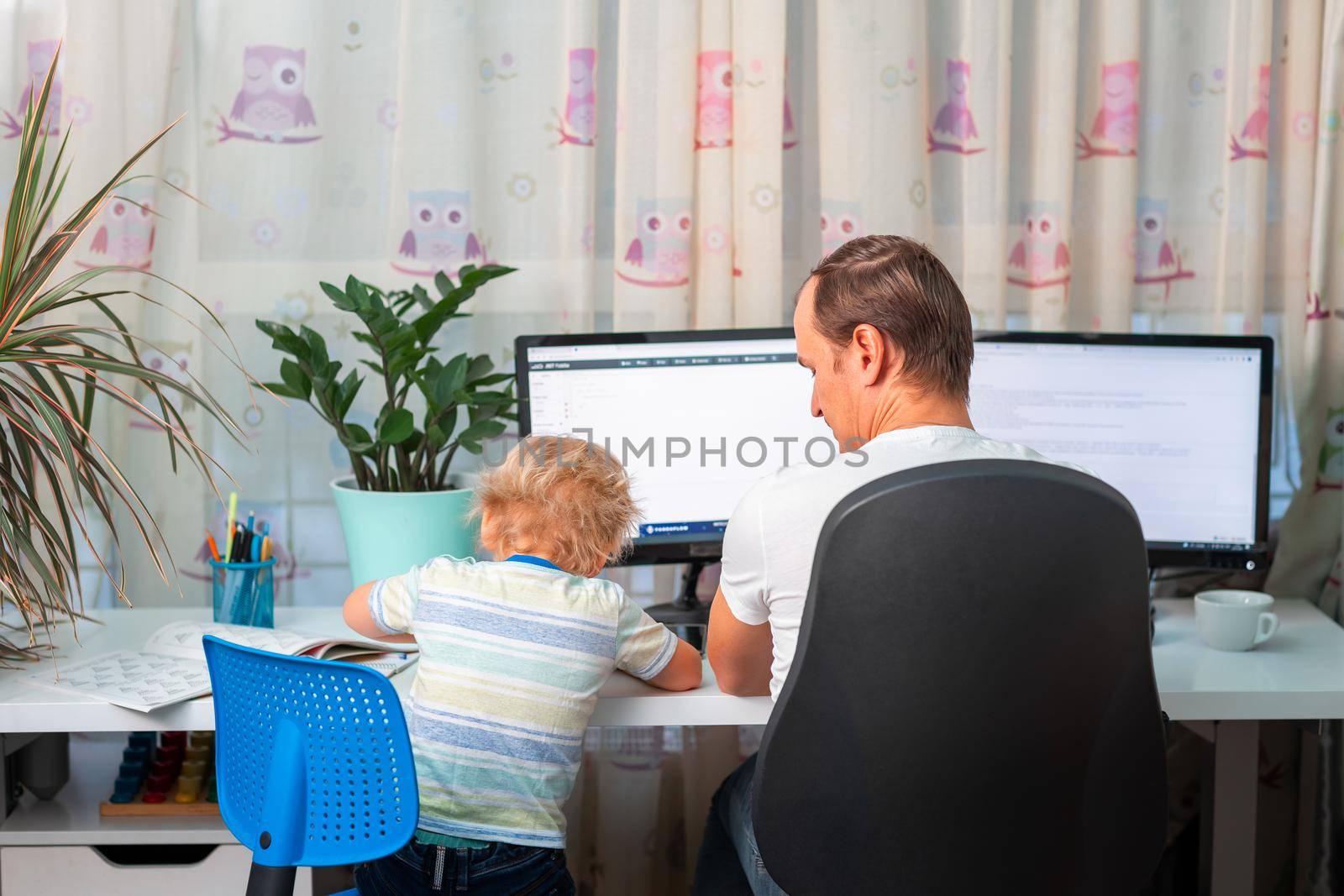 Father with kid trying to work from home during quarantine. Stay at home, work from home concept during coronavirus pandemic