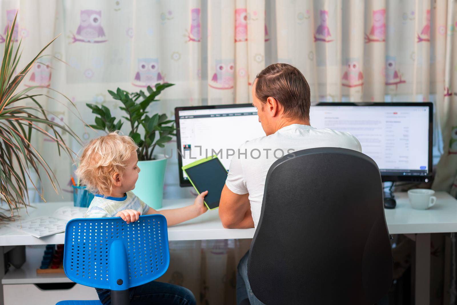 Father with kid trying to work from home during quarantine. Stay at home, work from home concept during coronavirus pandemic