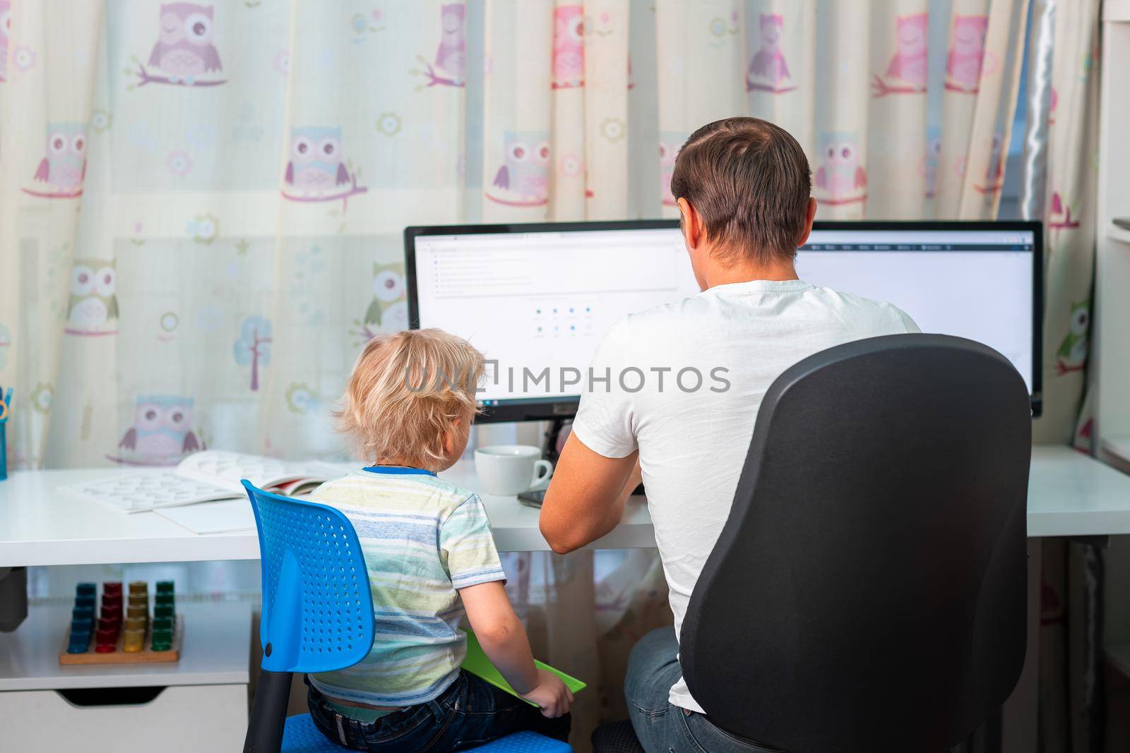 Father with kid trying to work from home during quarantine. Stay at home, work from home concept during coronavirus pandemic