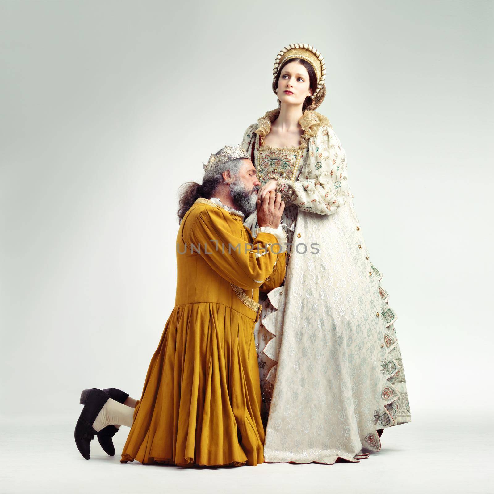 Studio shot of a king kneeling and kissing his queen's hand