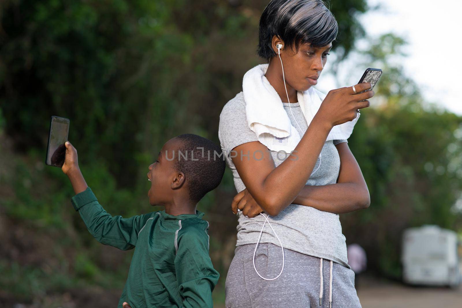 mother and son uses mobile phone outdoors after a fitness session together