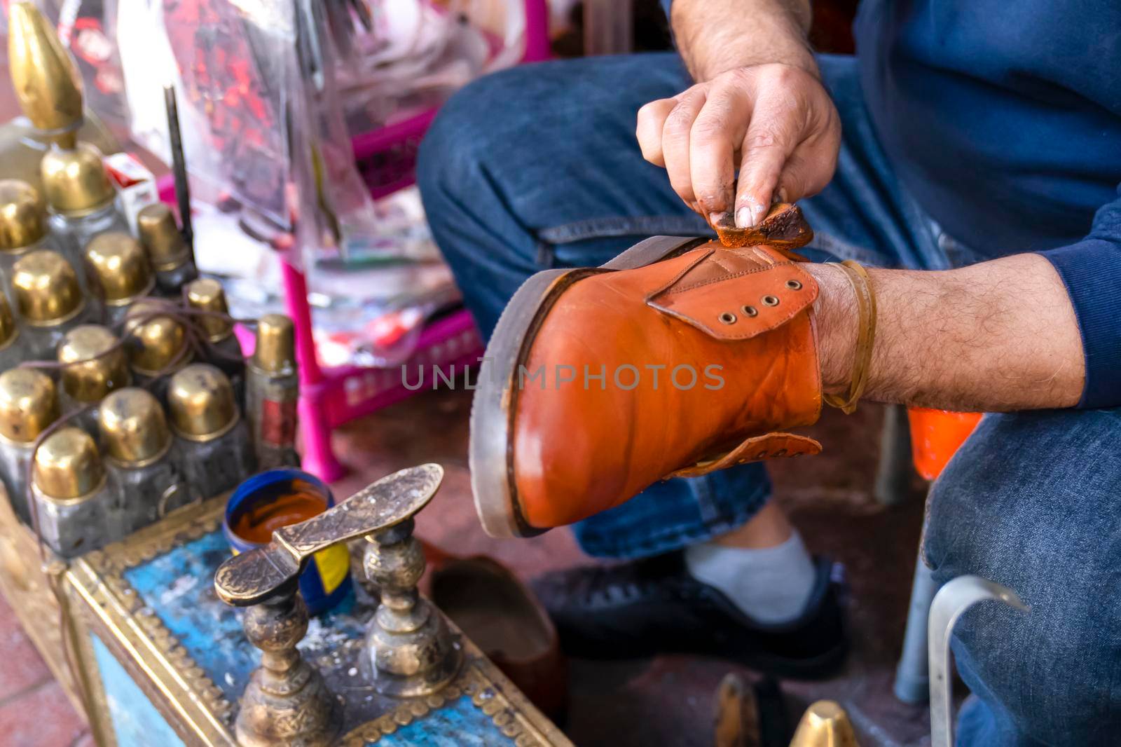 Man cleans shoes with shoe polish on street. Shoe shine. by Laguna781