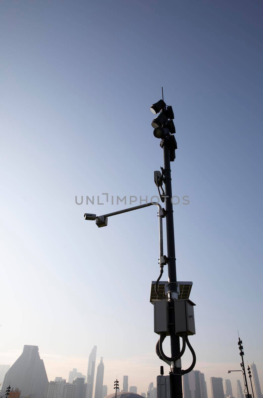 Modern public CCTV camera on pole with urban building in background by drpnncpp