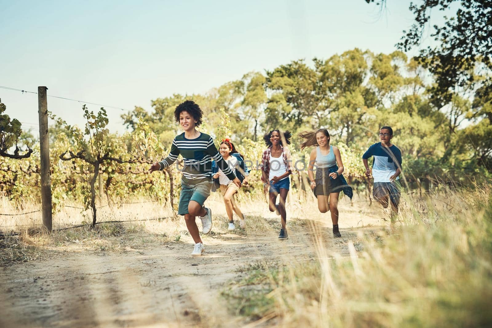 Run wild, run free. Shot of a group of teenagers running through nature at summer camp. by YuriArcurs