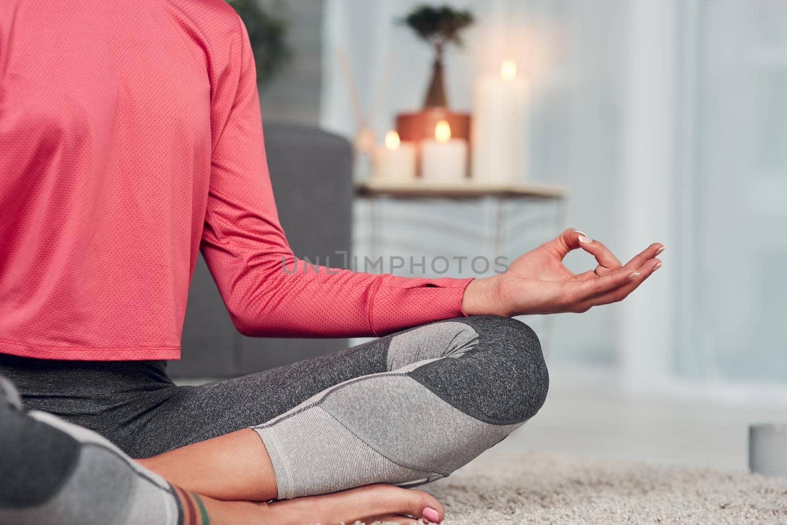Balancing my chakras. Cropped shot of an unrecognizable woman sitting cross legged and meditating in her living room while at home. by YuriArcurs